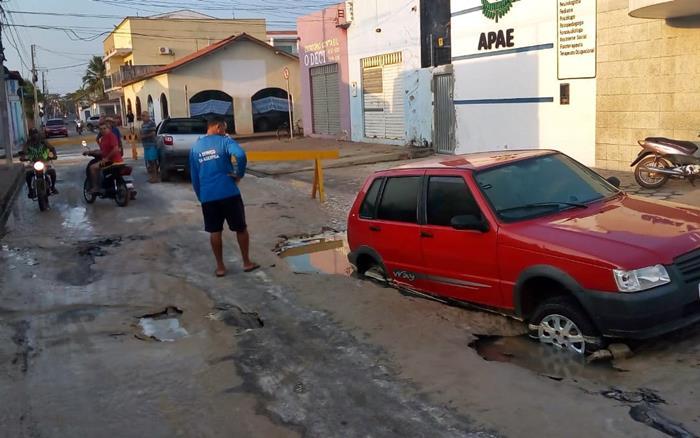 Carro fica atolado em buraco provocado por vazamento de água