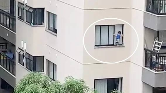 Criança pendurada em janela