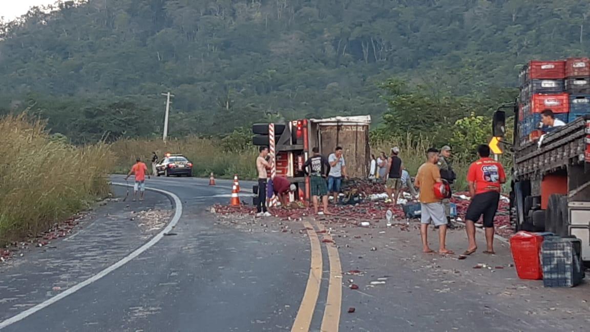 Caminhão  com a carga espalhada pela pista