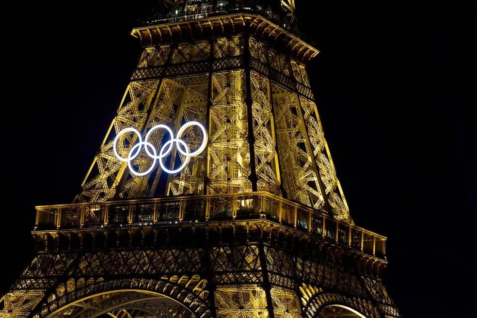 Torre Eiffel iluminada de noite com os anéis olímpicos