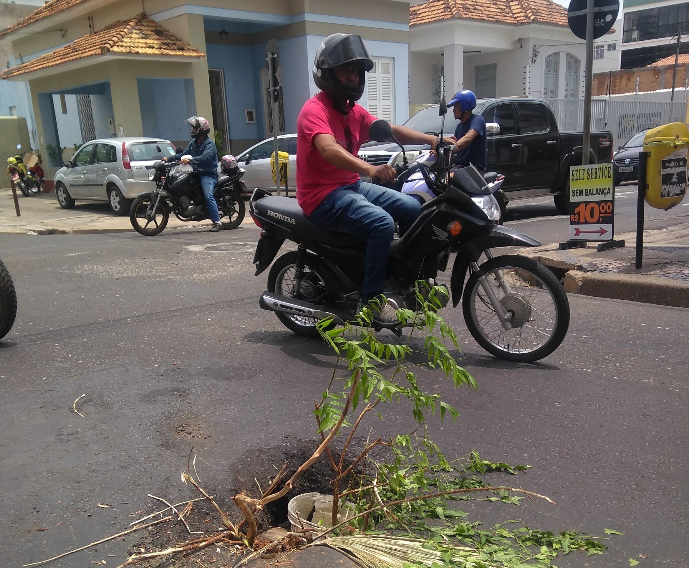Motoqueiro desviam do buraco com o alerta dos galhos vedes