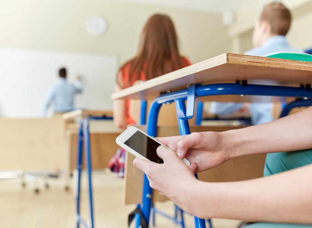 Adolescente mexendo no celular na escola