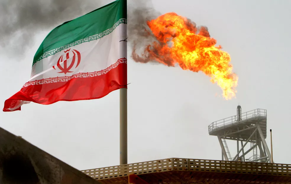 Tocha de gás em uma plataforma de produção de petróleo nos campos de petróleo de Soroush é vista ao lado de uma bandeira iraniana no Golfo Pérsico, no Irã